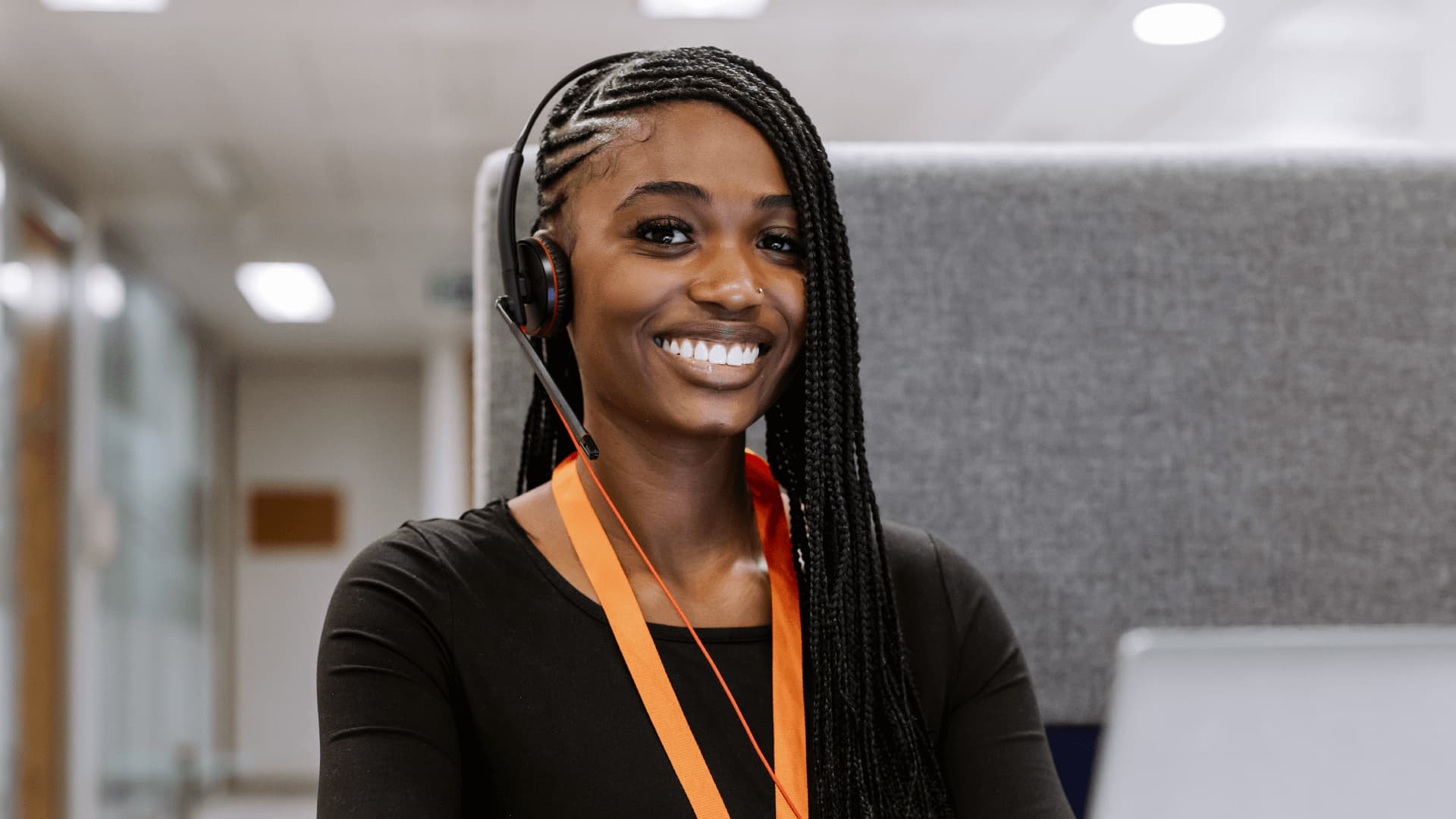 Headshot of Study Adviser Eniola wearing headset with braided hair in London office.