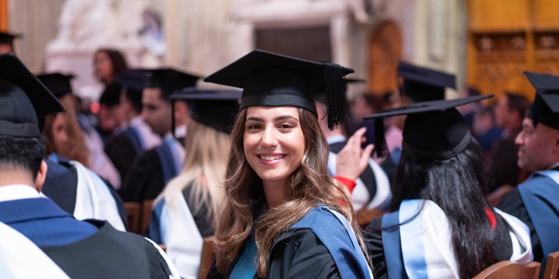 Smiling Walbrook and LIBF graduate with cap and gown in London Guildhall