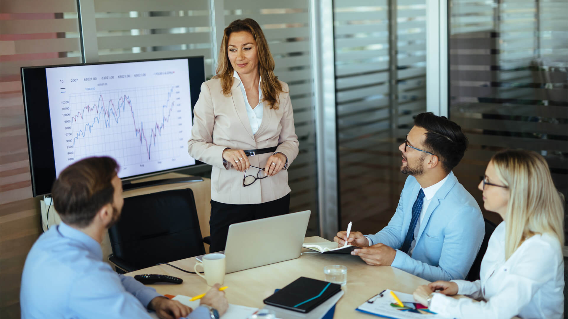 MBA Finance graduate presents data trends during a team discussion, encouraging strategic decision-making.