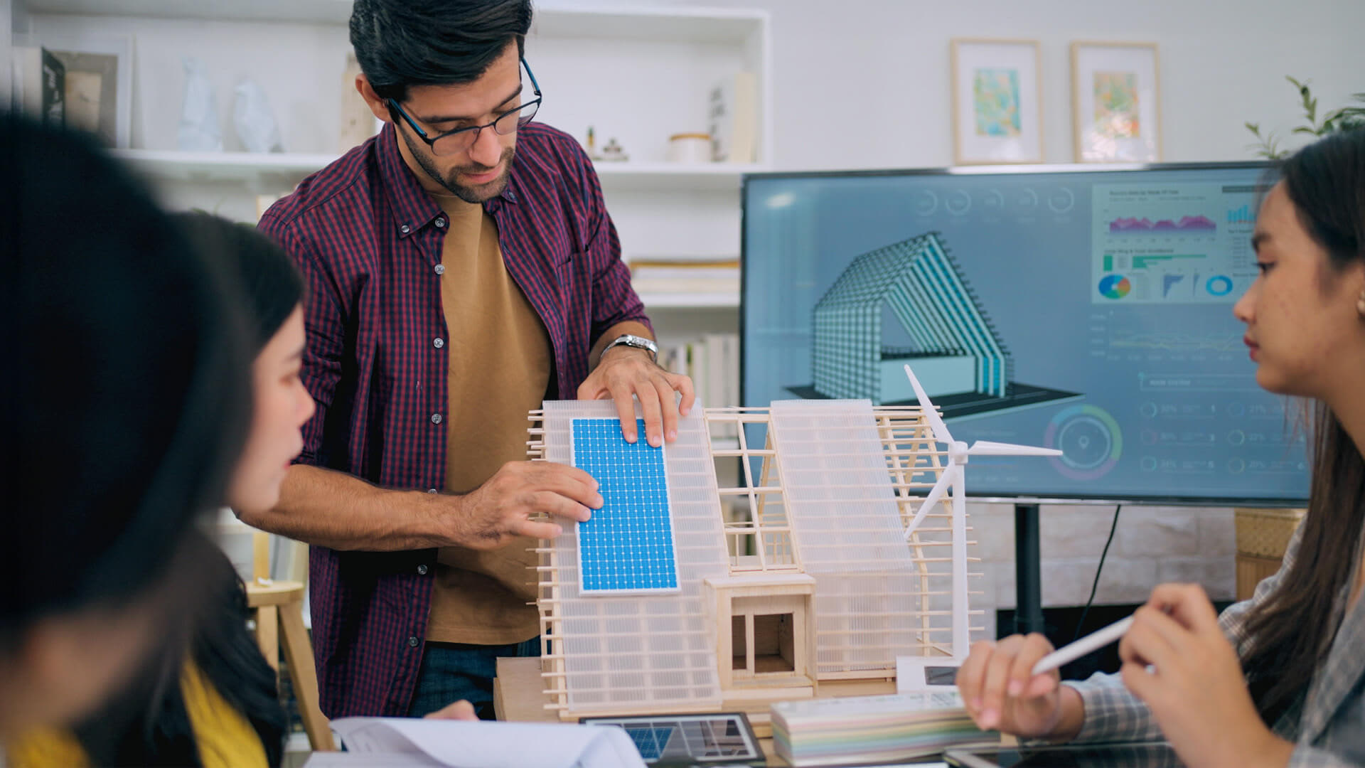 Focused MBA Innovation graduate explains renewable tech features during a workplace collaboration session.