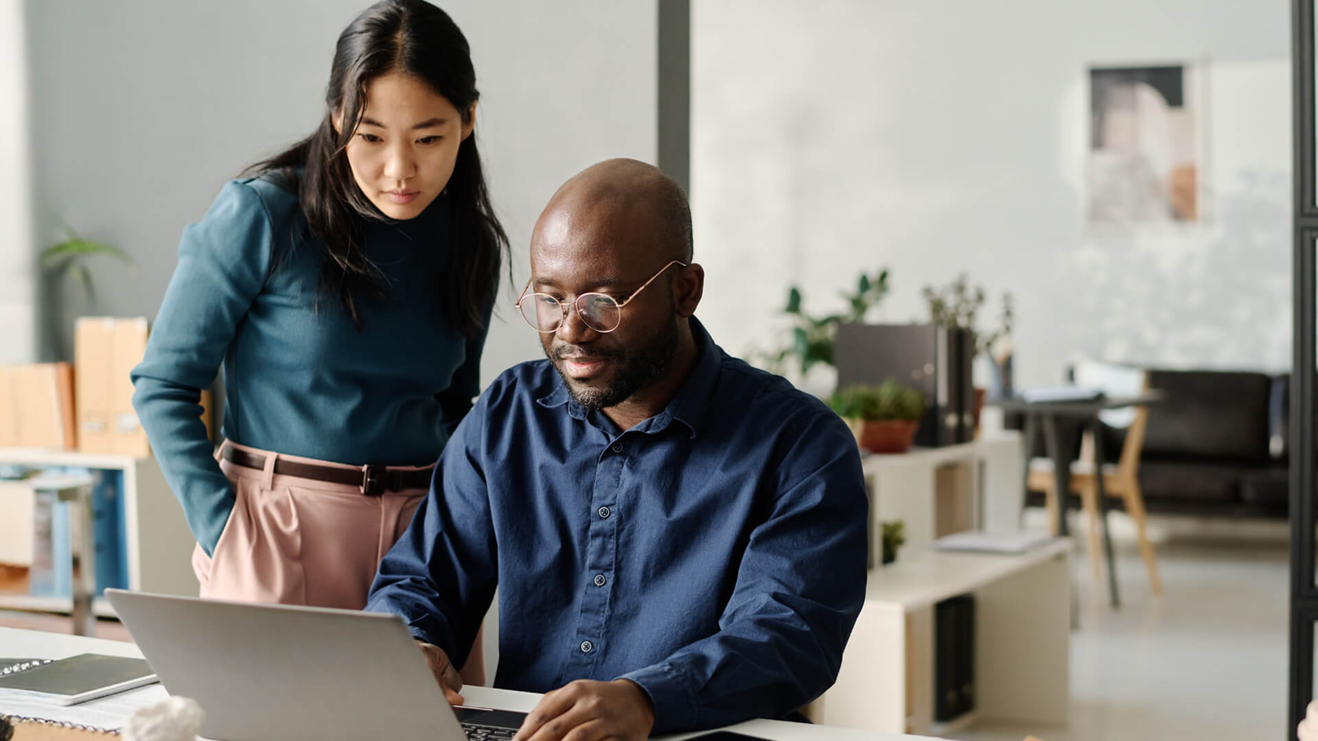 Online MBA alum collaborates on financial reports, combining analysis and teamwork in a modern workspace.