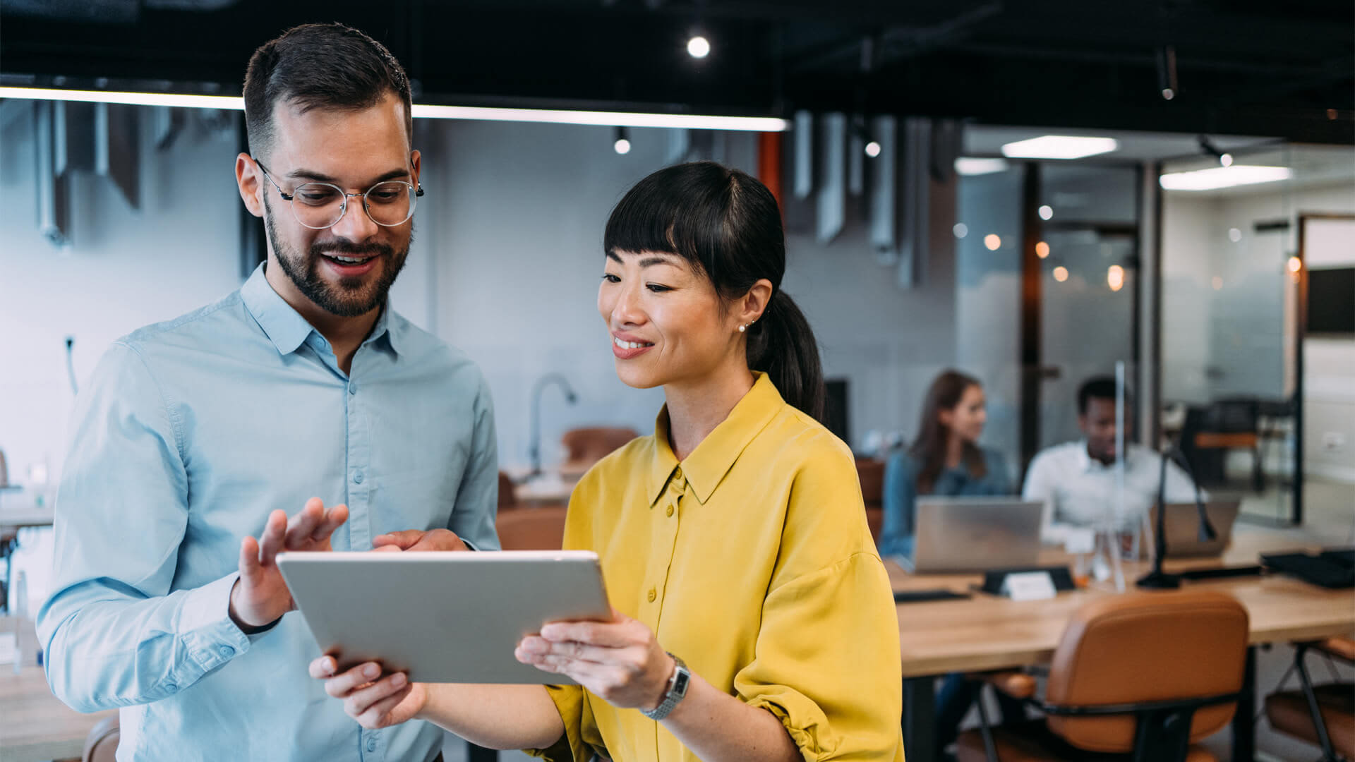 Colleagues reviewing an MBA Online project on a tablet, highlighting collaboration in a modern office.