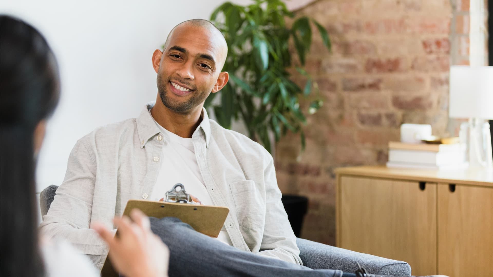 Male clinical psychologist in white shirt with clipboard explains key features of therapeutic care.