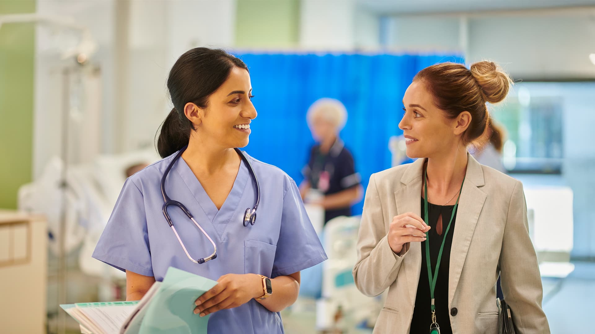A smiling hospital director speaking with a healthcare practitioner about patient care and wellfare.